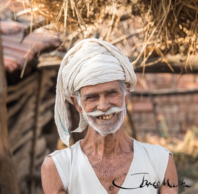 A smiling older man wearing a white head wrap